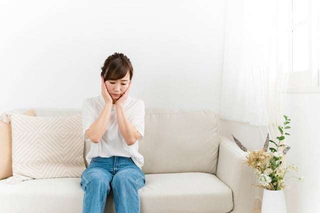 ソファに座って考える女性